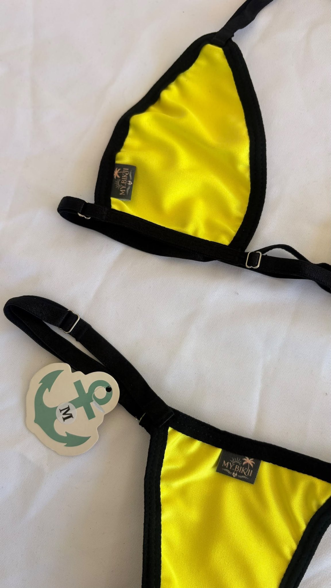 Détail d'un bikini jaune solaire avec liserés noirs et étiquette my.bikii.