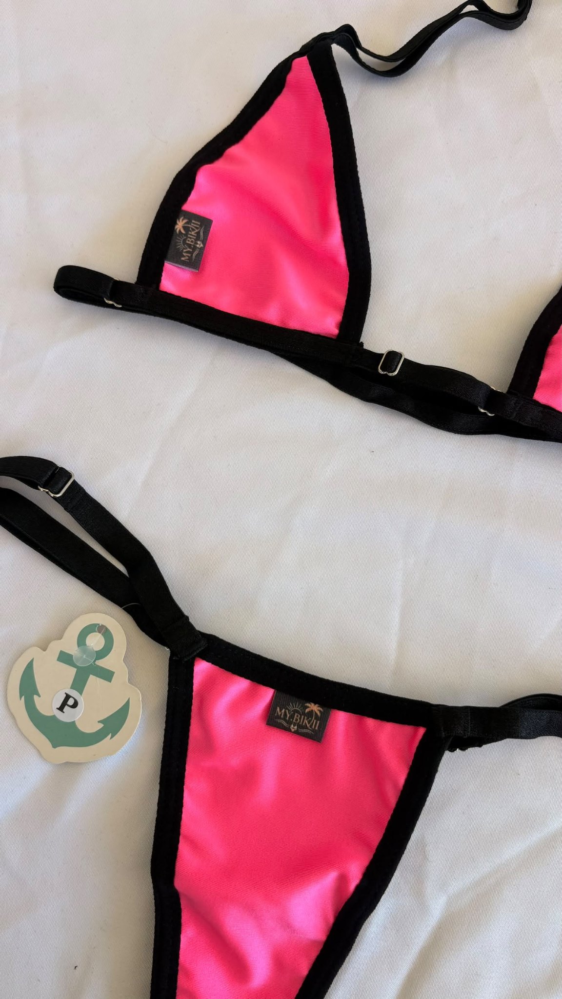Détail d'un bikini rose vif avec liserés blancs et noirs et étiquette my.bikii.