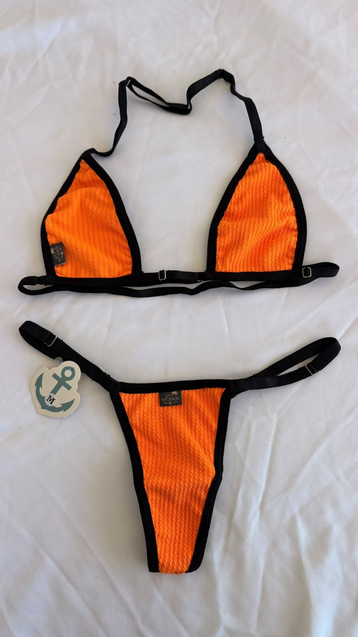 Ensemble bikini orange texturé avec liserés noirs, haut triangle et bas assorti.